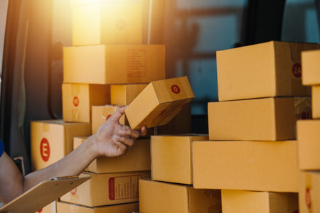 SME entrepreneur Small business entrepreneurs Online selling ideas,Happy Young Asian business owner work on computer and a boxs at home,delivery SME procurement package box deliver to customers,の写真素材