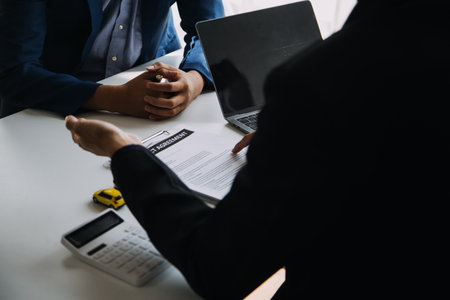 A car rental company employee is handing out the car keys to the renter after discussing the rental details and conditions together with the renter signing a car rental agreement. Concept car rental.の写真素材