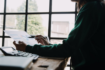 Attractive smiling young asian business woman work at home office, Asian woman working on laptop computer holding tablet.の写真素材
