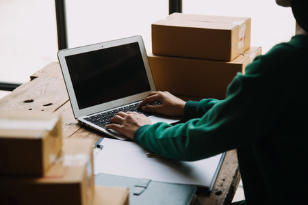 Startup small business entrepreneur or freelance Asian woman using a laptop with box, Young success Asian woman with her hand lift up, online marketing packaging box and delivery, SME concept.の写真素材