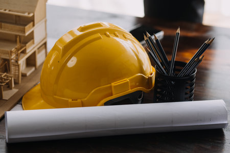 Image of engineering objects on workplace with three partners interacting on backgroundの写真素材
