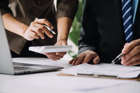 Financial analysts analyze business financial reports on a digital tablet planning investment project during a discussion at a meeting of corporate showing the results of their successful teamwork.の写真素材