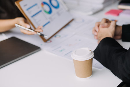 Financial analysts analyze business financial reports on a digital tablet planning investment project during a discussion at a meeting of corporate showing the results of their successful teamwork.の写真素材