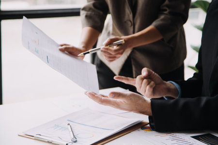 Financial analysts analyze business financial reports on a digital tablet planning investment project during a discussion at a meeting of corporate showing the results of their successful teamwork.の写真素材