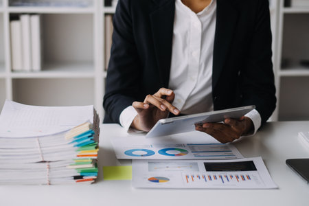 Financial analysts analyze business financial reports on a digital tablet planning investment project during a discussion at a meeting of corporate showing the results of their successful teamwork.の写真素材