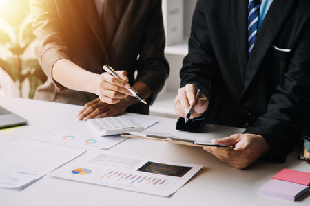 Financial analysts analyze business financial reports on a digital tablet planning investment project during a discussion at a meeting of corporate showing the results of their successful teamwork.の写真素材