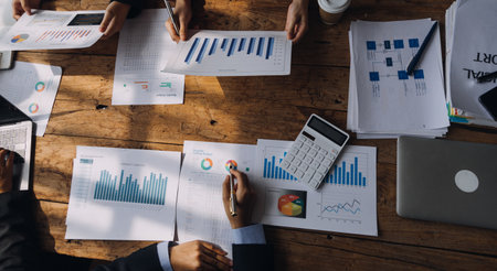 Financial analysts analyze business financial reports on a digital tablet planning investment project during a discussion at a meeting of corporate showing the results of their successful teamwork.の写真素材