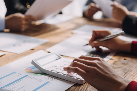 Financial analysts analyze business financial reports on a digital tablet planning investment project during a discussion at a meeting of corporate showing the results of their successful teamwork.の写真素材