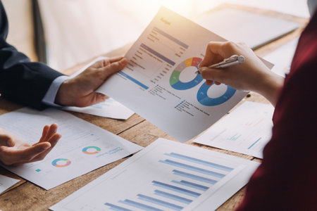Financial analysts analyze business financial reports on a digital tablet planning investment project during a discussion at a meeting of corporate showing the results of their successful teamwork.の写真素材