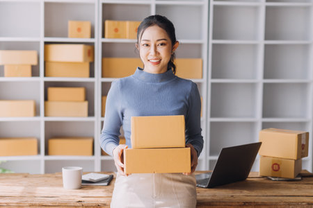 Startup SME small business entrepreneur of freelance Asian woman using a laptop with box Cheerful...