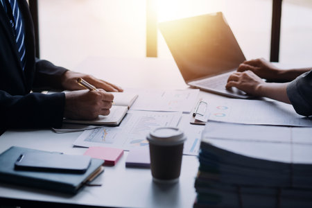 Financial analysts analyze business financial reports on a digital tablet planning investment project during a discussion at a meeting of corporate showing the results of their successful teamwork.の写真素材