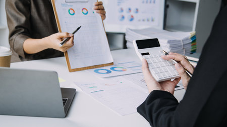 Financial analysts analyze business financial reports on a digital tablet planning investment project during a discussion at a meeting of corporate showing the results of their successful teamwork.の写真素材