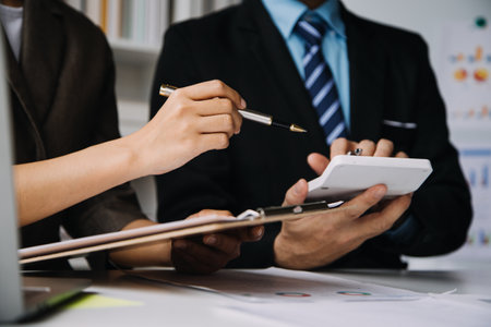 Financial analysts analyze business financial reports on a digital tablet planning investment project during a discussion at a meeting of corporate showing the results of their successful teamwork.の写真素材
