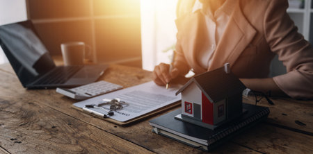 Real estate broker agent presenting and consult to customer to decision making sign insurance form agreement, buy and sell home model, concerning mortgage loan offer for and house insuranceの写真素材