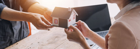 Real estate broker agent presenting and consult to customer to decision making sign insurance form agreement, buy and sell home model, concerning mortgage loan offer for and house insuranceの写真素材