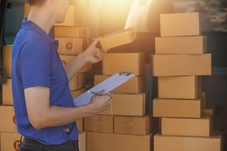 Parcel boxes on shelf and color shopping bags placing near laptop on table. SME business on shopping online at home office packaging on background is popular business.の写真素材