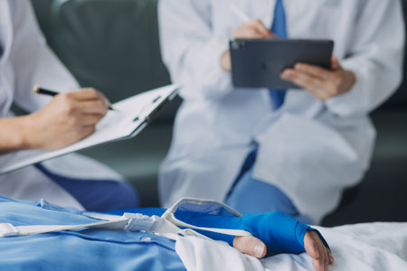 Man with broken arm in cast lying on bed in hospital. The emergency center treatment is plaster and hangs with sling for a further cure in an orthopedic clinic. Patient pain from accident injury.の写真素材