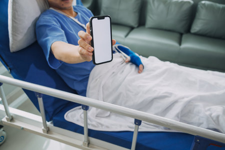 Man with broken arm in cast lying on bed in hospital. The emergency center treatment is plaster and hangs with sling for a further cure in an orthopedic clinic. Patient pain from accident injury.の写真素材