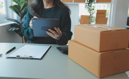 Entrepreneurs Small Business SME Independent men work at home Use smartphones and laptops for commercial checking, online marketing, packing boxes, SME sellers, concept, e-commerce team, online salesの写真素材