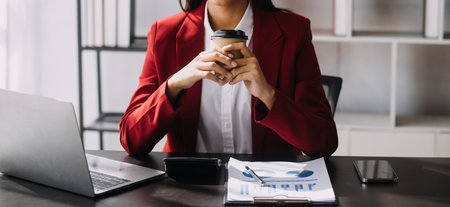 Asian Business woman using calculator and laptop for doing math finance on an office desk, tax, report, accounting, statistics, and analytical research conceptの写真素材