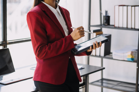 Asian Business woman using calculator and laptop for doing math finance on an office desk, tax, report, accounting, statistics, and analytical research conceptの写真素材