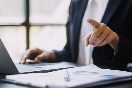 Asian Business woman using calculator and laptop for doing math finance on an office desk, tax, report, accounting, statistics, and analytical research conceptの写真素材