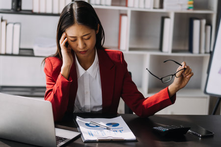 Asian women are stressed while working on laptop, Tired asian businesswoman with headache at office, feeling sick at work, copy spaceの写真素材