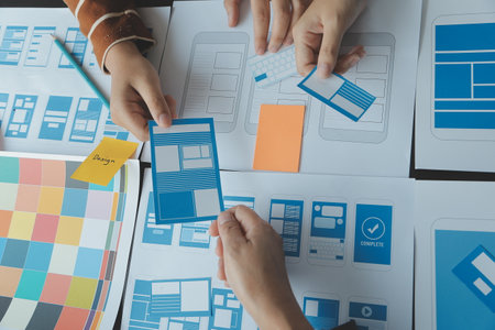 Close up ux developer and ui designer brainstorming about mobile app interface wireframe design on table with customer breif and color code at modern office.Creative digital development agencyの写真素材