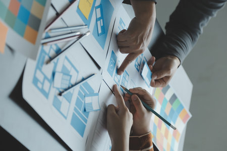 Close up ux developer and ui designer brainstorming about mobile app interface wireframe design on table with customer breif and color code at modern office.Creative digital development agencyの写真素材