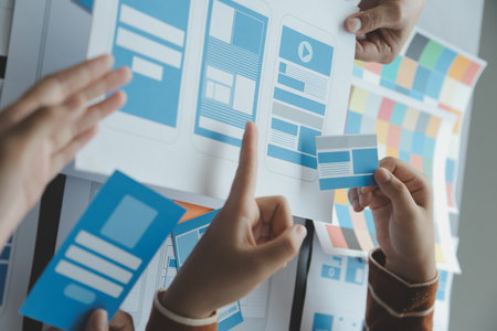 Close up ux developer and ui designer brainstorming about mobile app interface wireframe design on table with customer breif and color code at modern office.Creative digital development agencyの写真素材