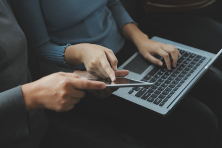 Beautiful woman sitting on a outdoors and using at laptop. Woman and friend having fun with new technology and shopping online at outdoor place.の写真素材