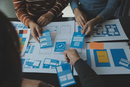 Close up ux developer and ui designer brainstorming about mobile app interface wireframe design on table with customer breif and color code at modern office.Creative digital development agencyの写真素材