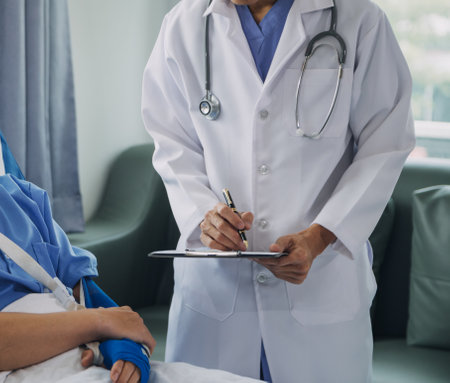 Injured patient showing doctor broken wrist and arm with bandage in hospital office or emergency room. Sprain, stress fracture or repetitive strain injury in hand. Nurse helping customer. First aid.の写真素材