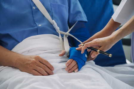 Injured patient showing doctor broken wrist and arm with bandage in hospital office or emergency room. Sprain, stress fracture or repetitive strain injury in hand. Nurse helping customer. First aid.の写真素材