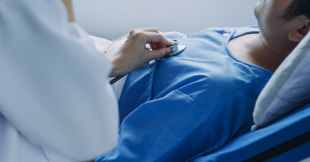 Side view of diverse doctors examining Asian female patient in bed in ward at hospital.の写真素材