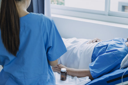 Side view of diverse doctors examining Asian female patient in bed in ward at hospital.の写真素材
