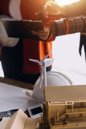 Three colleagues discussing data working and tablet, laptop with on on architectural project at construction site at desk in officeの写真素材