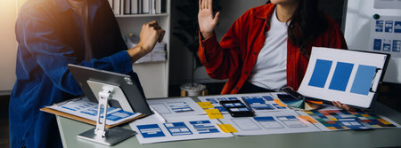 Close up ux developer and ui designer brainstorming about mobile app interface wireframe design on table with customer breif and color code at modern office.Creative digital development agencyの写真素材