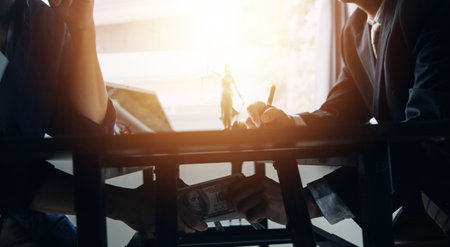 Justice and Law concept. Legal counsel presents to the client a signed contract with gavel and legal law or legal having team meeting at law firm in backgroundの写真素材