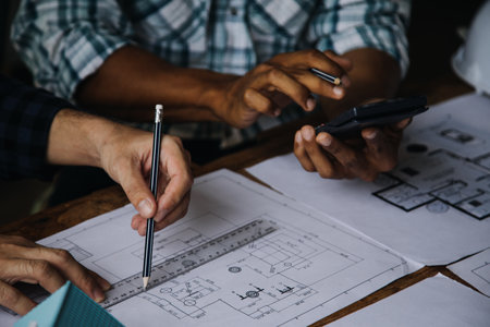 Image of engineering objects on workplace with three partners interacting on backgroundの写真素材