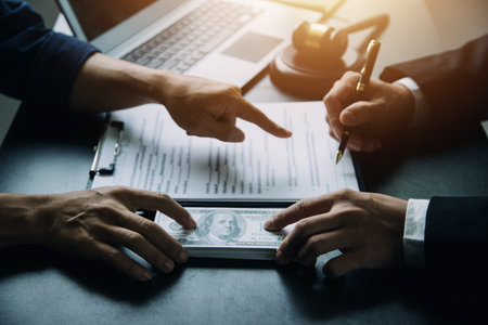 Justice and Law concept. Legal counsel presents to the client a signed contract with gavel and legal law or legal having team meeting at law firm in backgroundの写真素材