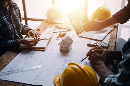 Image of engineering objects on workplace with three partners interacting on backgroundの写真素材