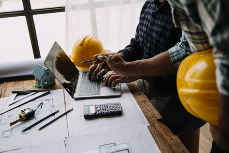 Image of engineering objects on workplace with three partners interacting on backgroundの写真素材
