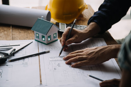 Image of engineering objects on workplace with three partners interacting on backgroundの写真素材