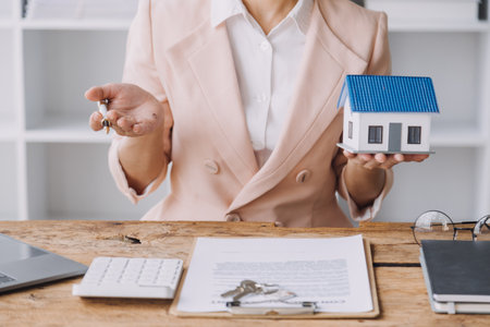 Real estate brokerage agent Deliver a sample of a model house to the customer, mortgage loan agreement Making lease and buying a house And contract home insurance conceptの写真素材