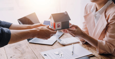 Real estate brokerage agent Deliver a sample of a model house to the customer, mortgage loan agreement Making lease and buying a house And contract home insurance conceptの写真素材