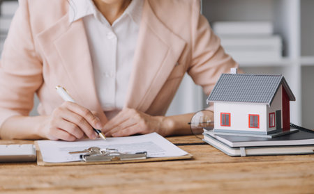 Real estate brokerage agent Deliver a sample of a model house to the customer, mortgage loan agreement Making lease and buying a house And contract home insurance conceptの写真素材