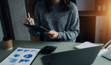 Financial analysts analyze business financial reports on a digital tablet planning investment project during a discussion at a meeting of corporate showing the results of their successful teamwork.の写真素材