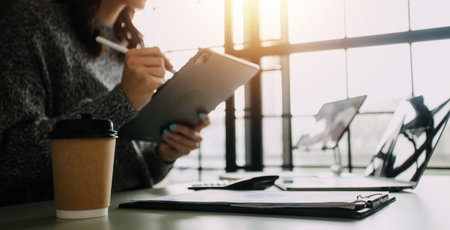 Financial analysts analyze business financial reports on a digital tablet planning investment project during a discussion at a meeting of corporate showing the results of their successful teamwork.の写真素材