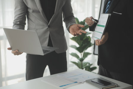 Financial analysts analyze business financial reports on a digital tablet planning investment project during a discussion at a meeting of corporate showing the results of their successful teamwork.の写真素材